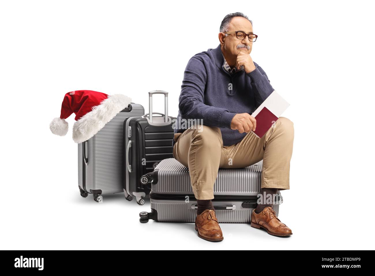 Pensive mature man sitting on a suitcase and waiting with a passport, delayed christmas flight concept Stock Photo