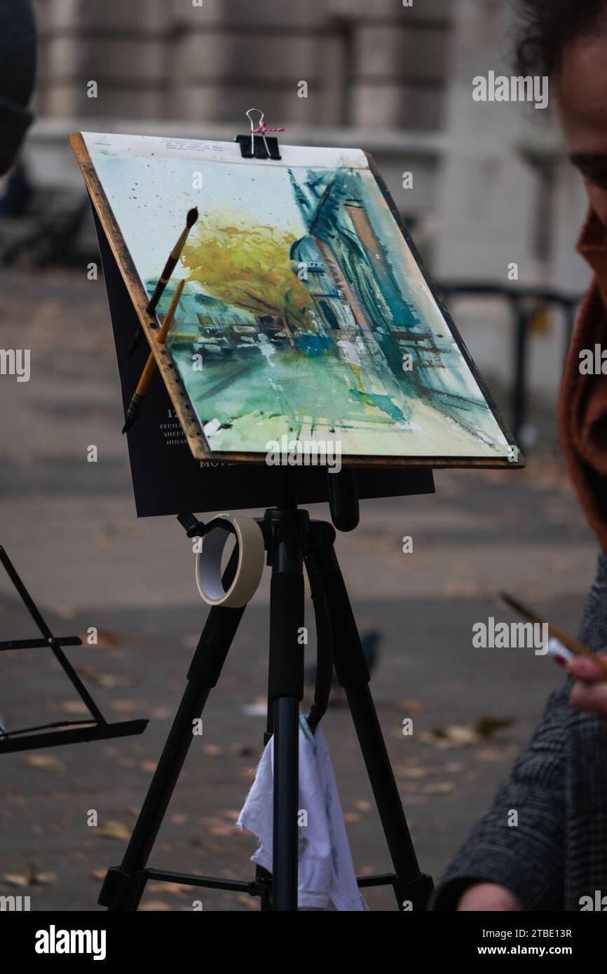 This image showcases a creative artist painting on an easel with a joyful expression on their face Stock Photo
