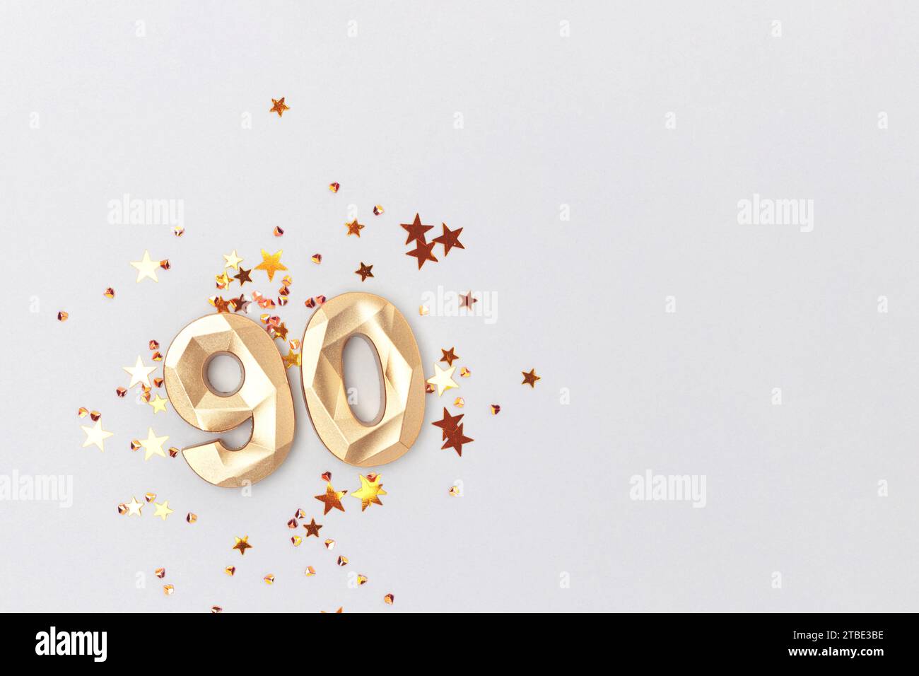 Golden number 90 and glowing stars confetti on a blue background. Festive composition. Stock Photo