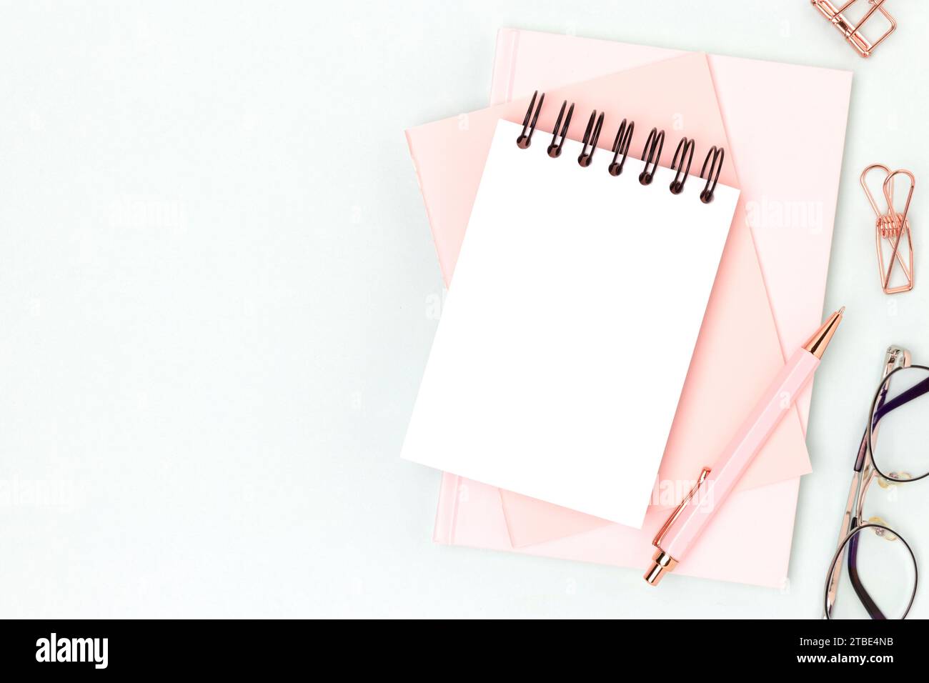Workspace with empty notepad mockup and pink colored stationery on a blue background. Office supplies. Stock Photo