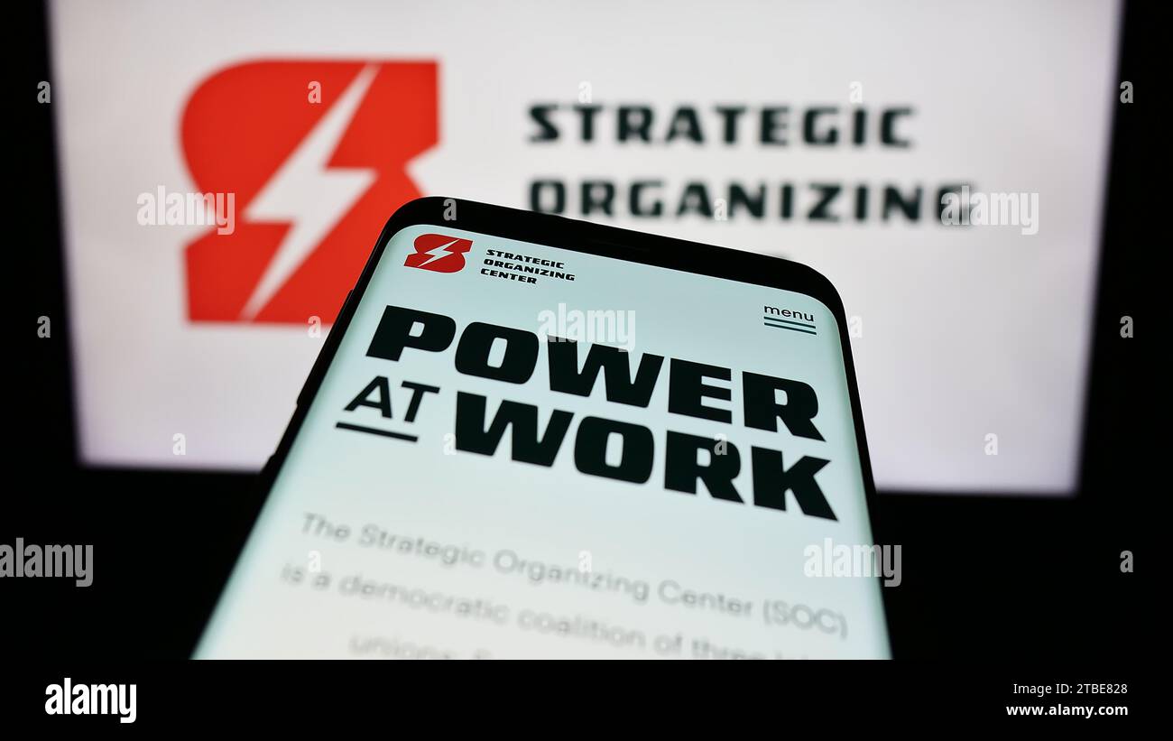 Mobile phone with website of labor union coalition Strategic Organizing Center (SOC) in front of logo. Focus on top-left of phone display. Stock Photo