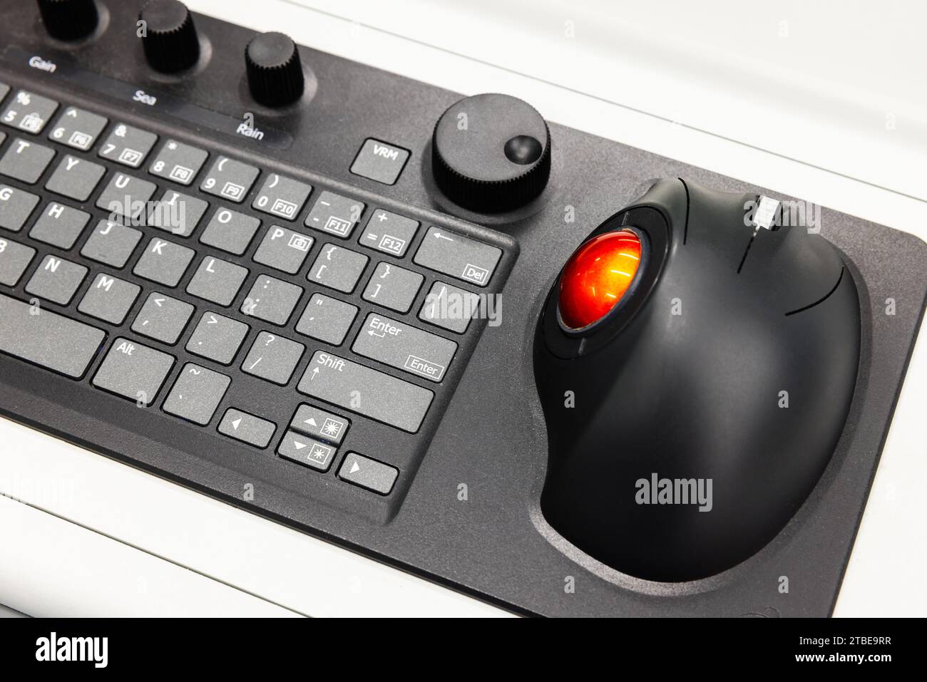 Built-in tabletop input device, black industrial keyboard with red trackball mouse, modern navigation equipment mounted on a control panel at captains Stock Photo