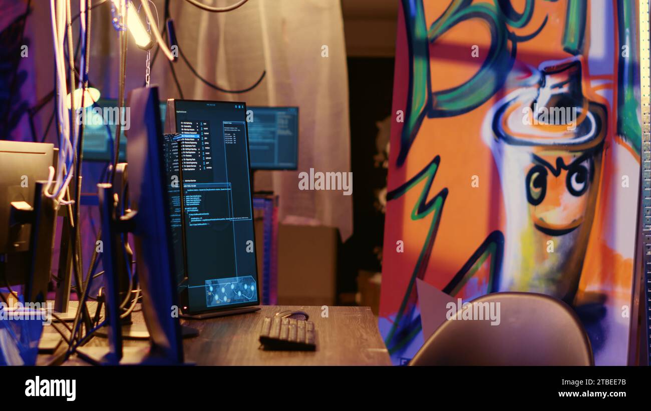 Graffiti painted empty hideaway base with lines of code running on computer screen with malware that get past security systems. PCs in deserted bunker showing scripts that can hack devices Stock Photo