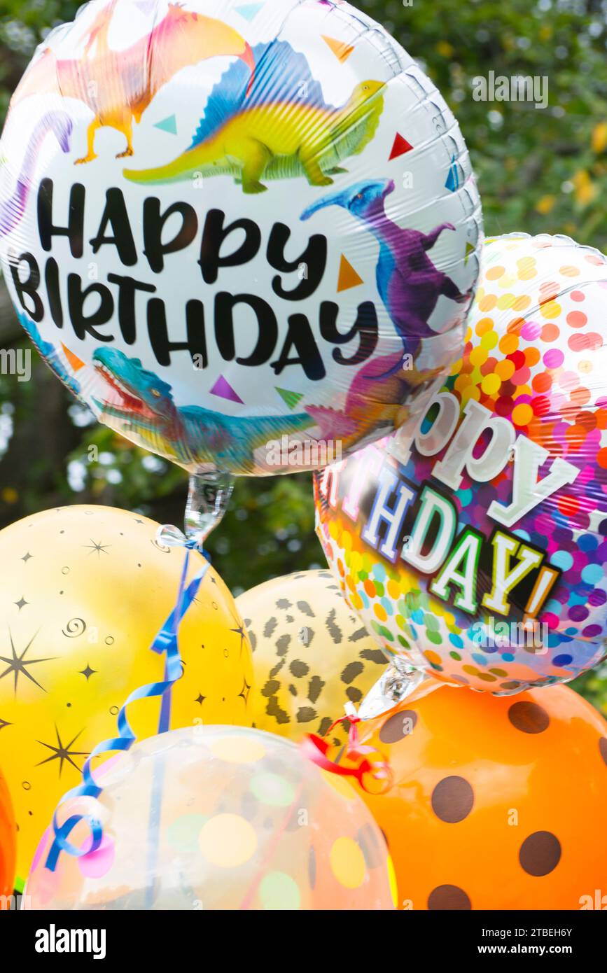 Several 'Happy Birthday' and colorful helium-filled balloons in an outdoor setting Stock Photo