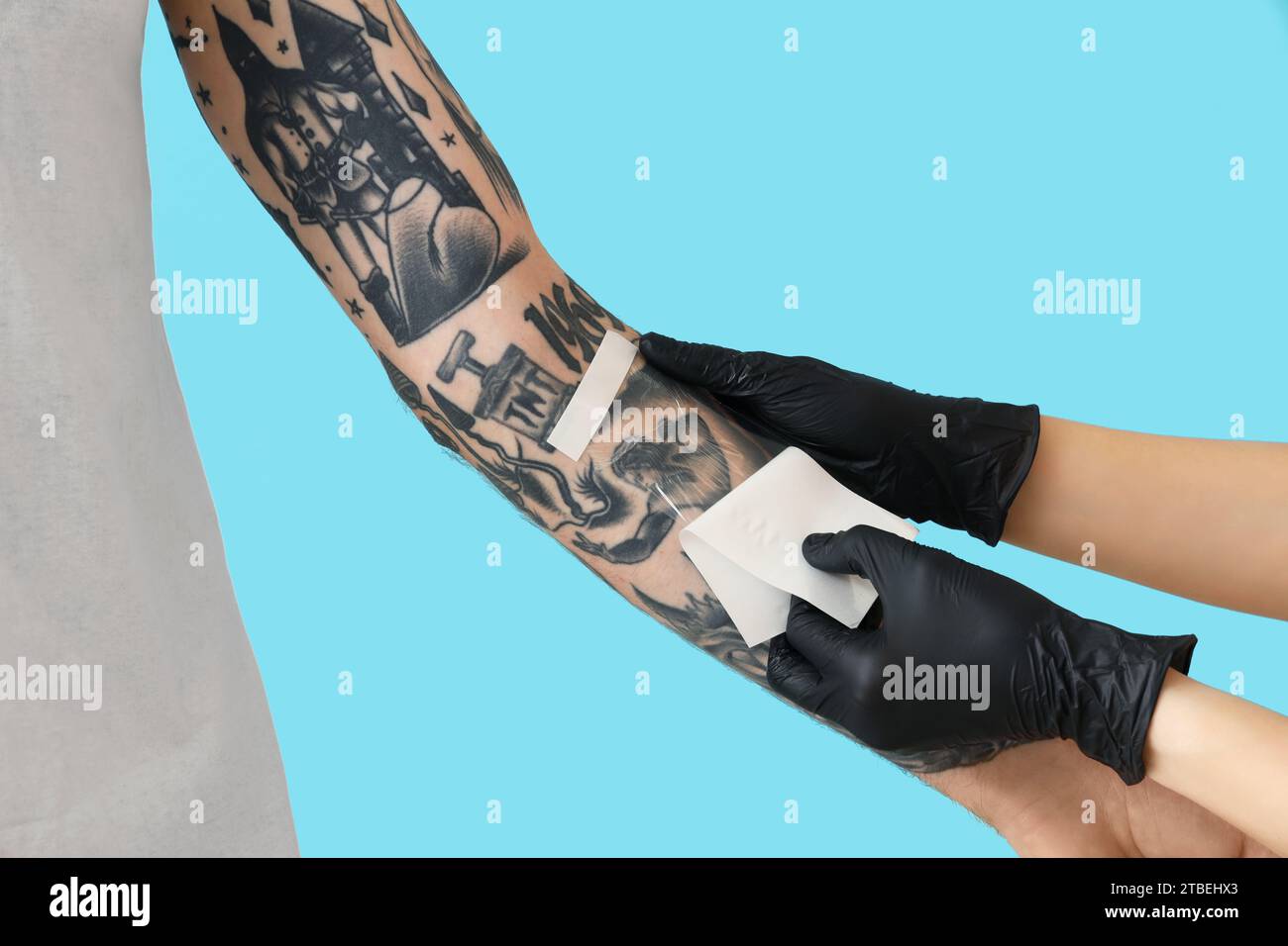 Tattoo master in gloves applying protective film cover over fresh
