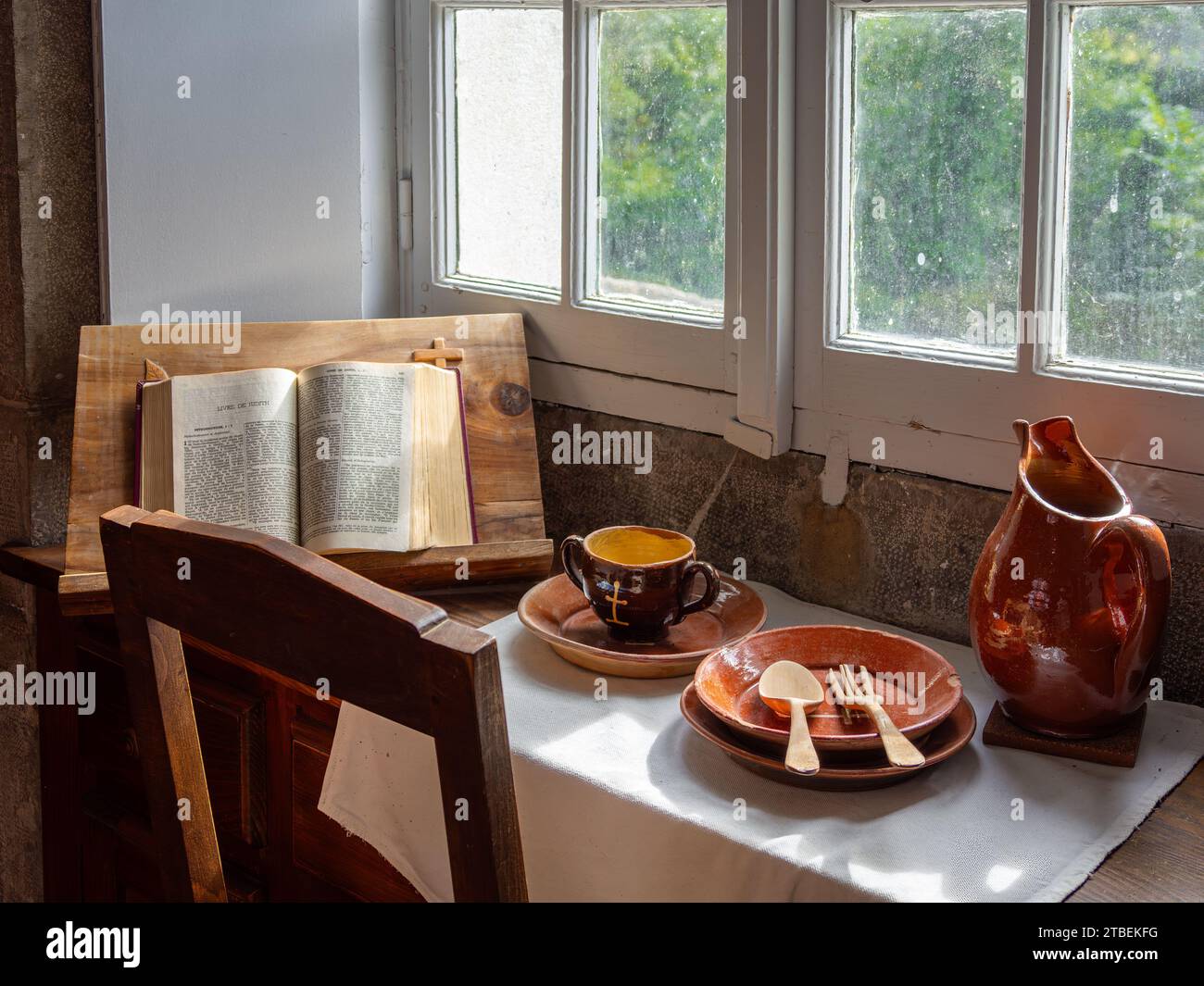Grande Chartreuse, France - September 30, 2023: Objects on a monk's desk in the Carthusian monastery of the Grande Chartreuse: Bible, ceramic dish, wa Stock Photo