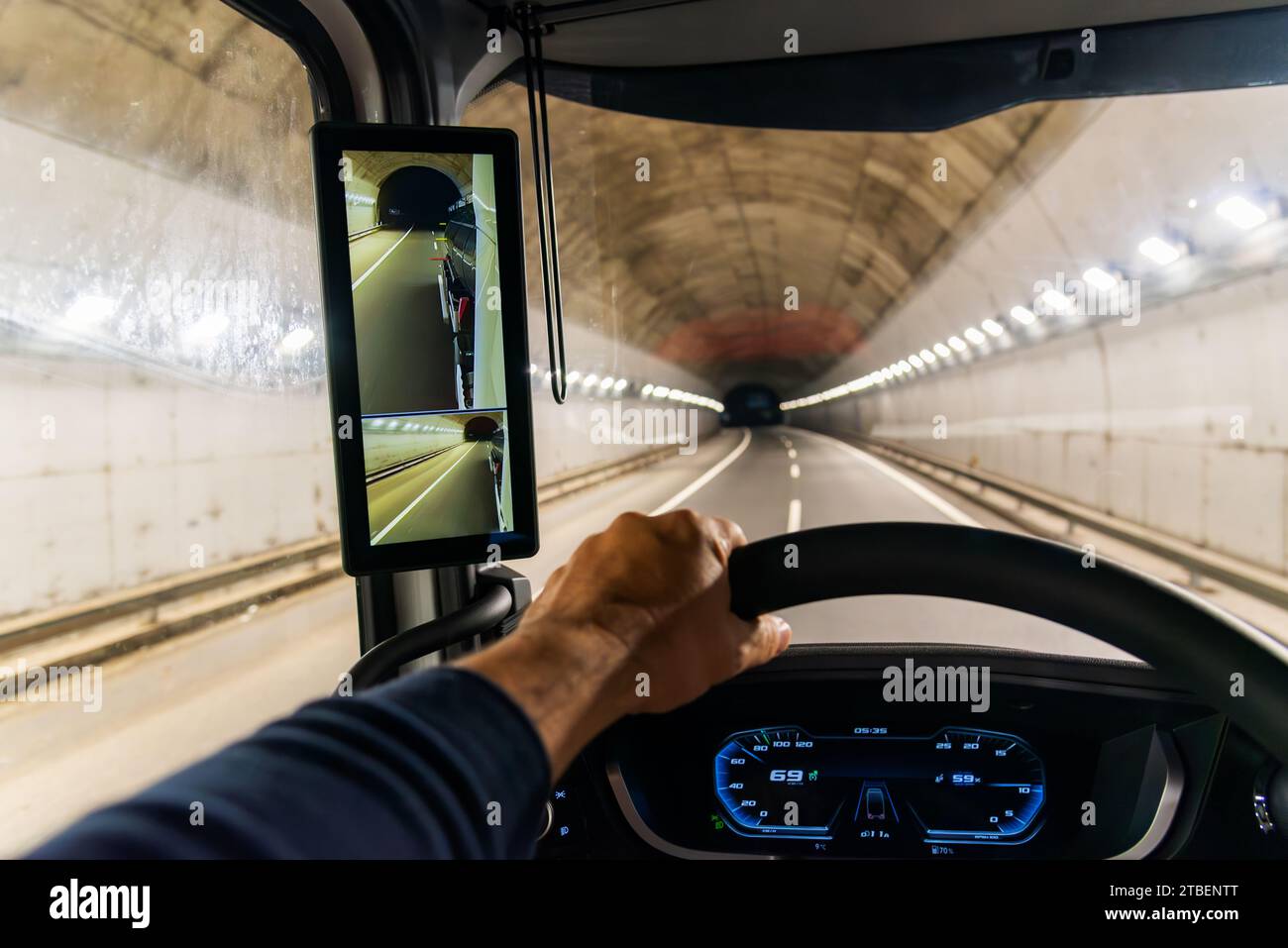View from the driving position of a truck of the interior of a highway tunnel and a screen as a rearview mirror. Stock Photo