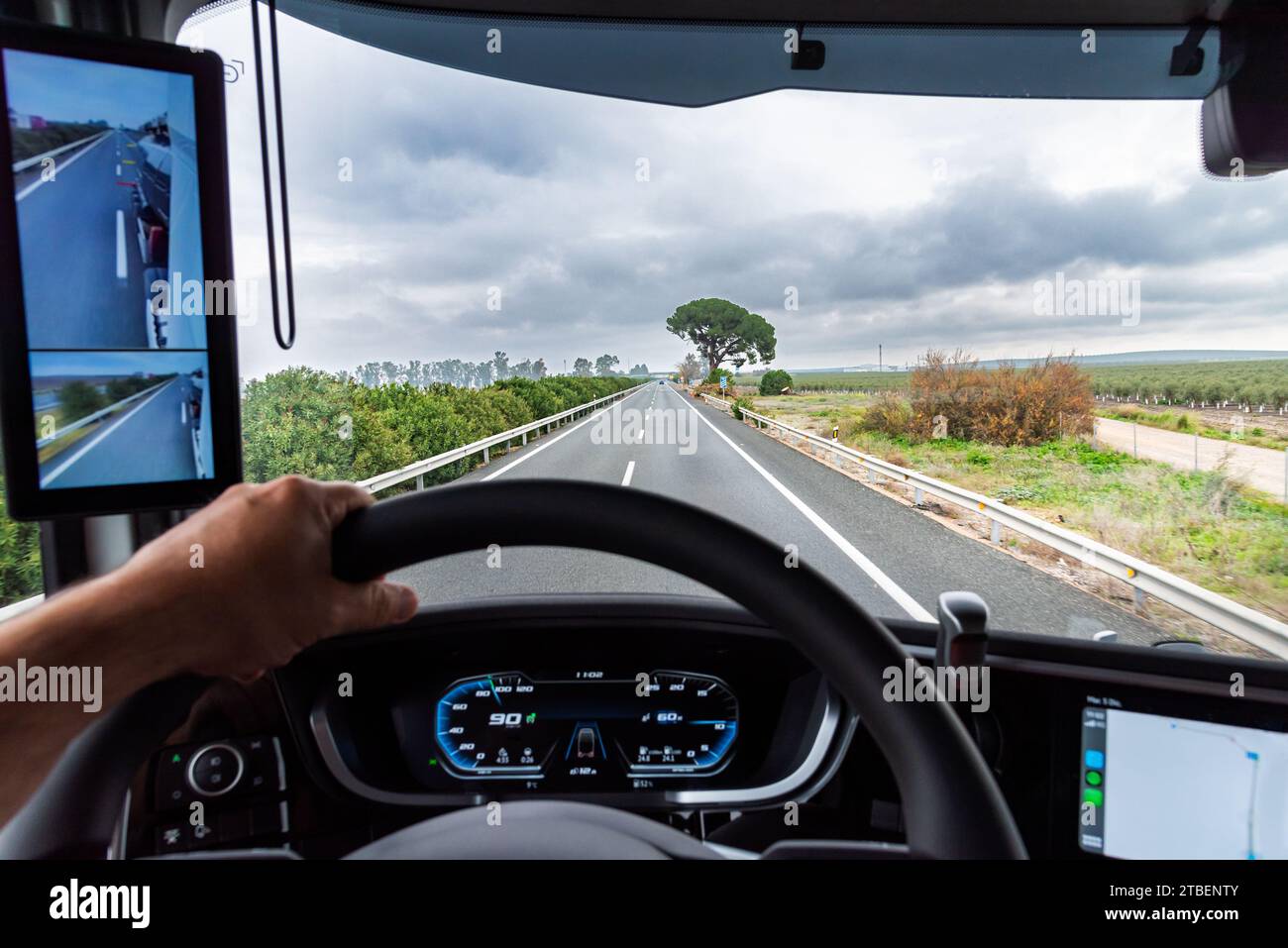 View from the driving position of a truck on a highway next to the field. Stock Photo