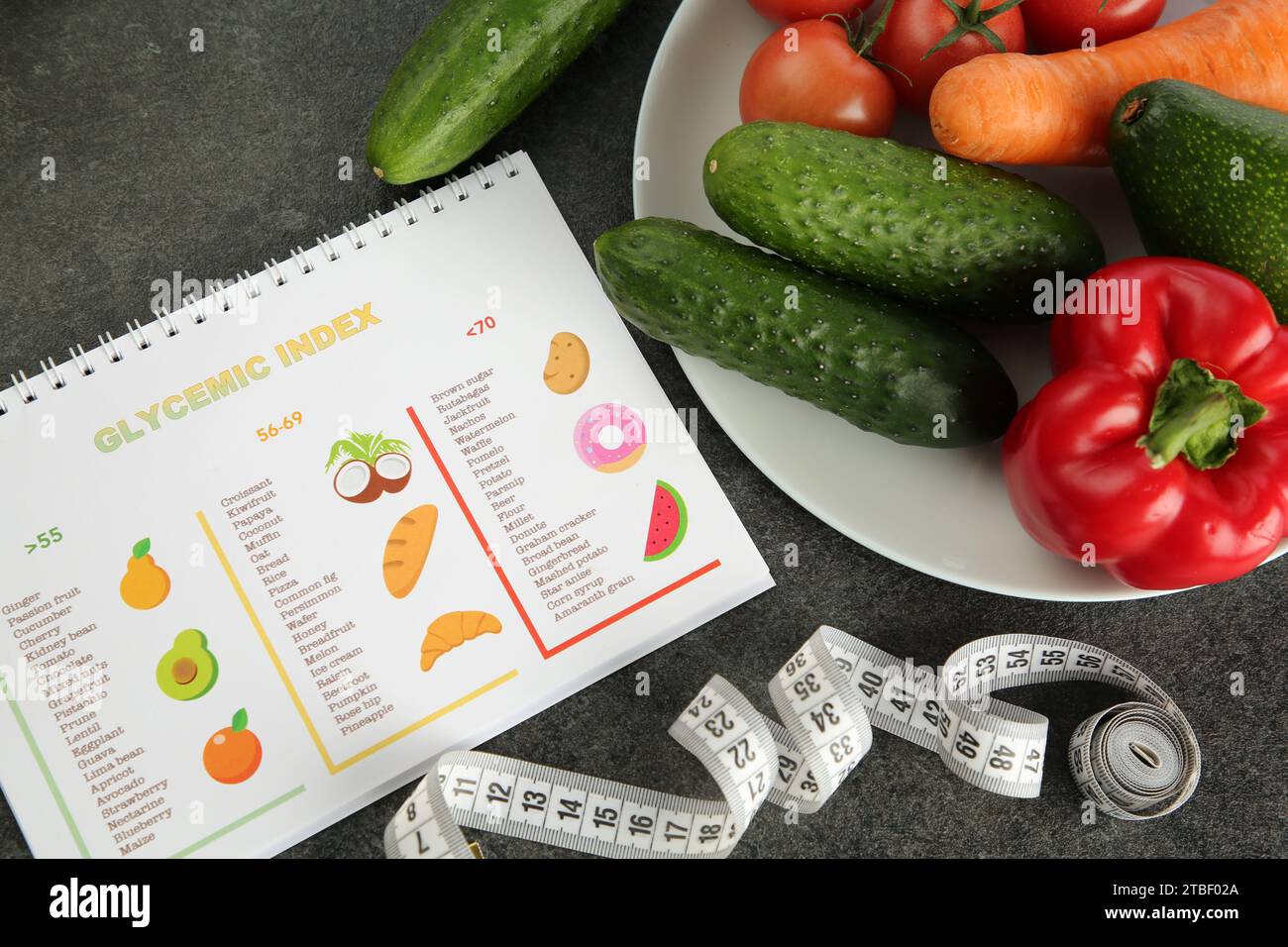 Notebook with information about glycemic index, measuring tape and vegetables on grey table, flat lay Stock Photo