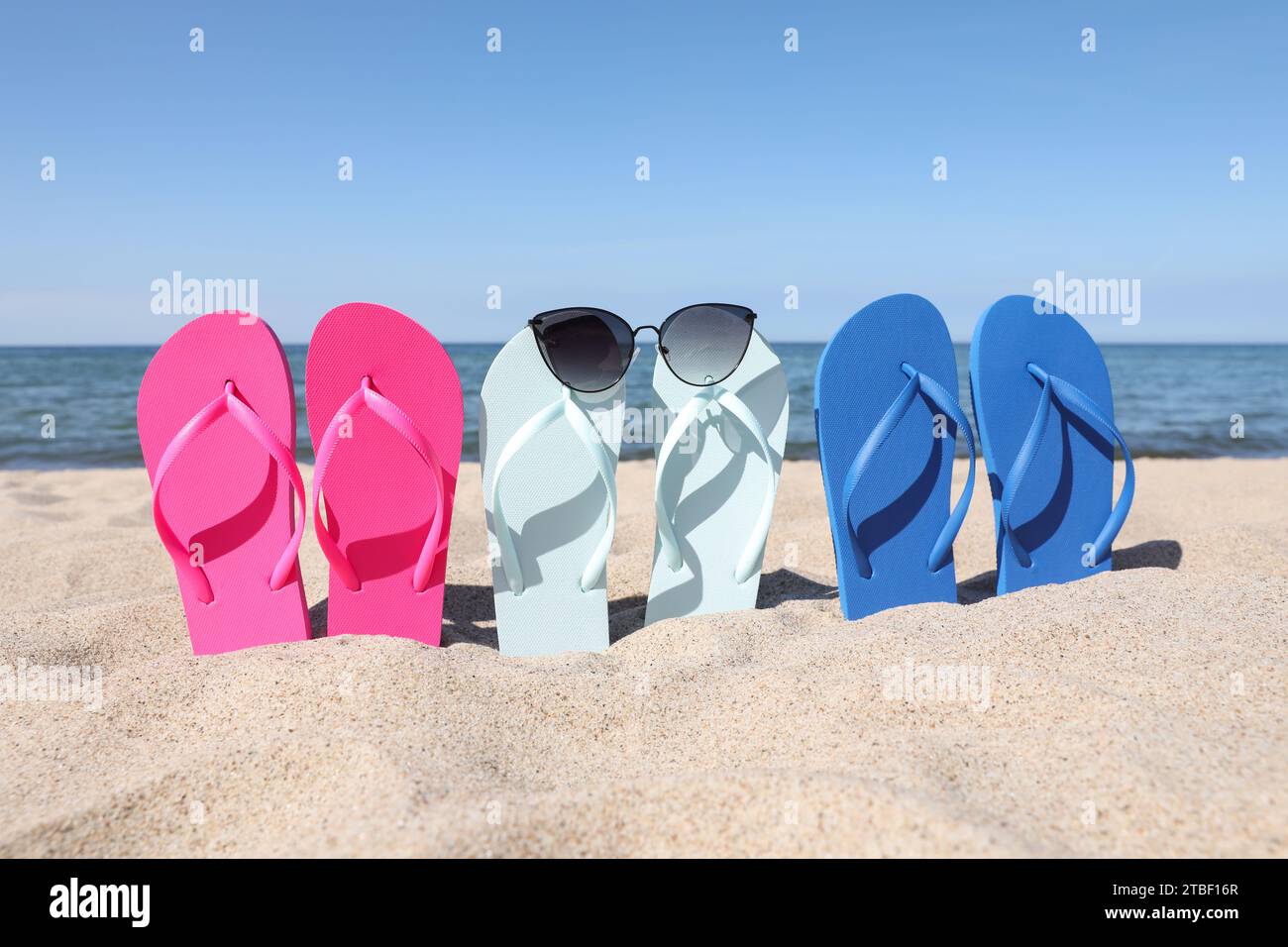 Stylish colorful flip flops and sunglasses on beach sand Stock Photo ...