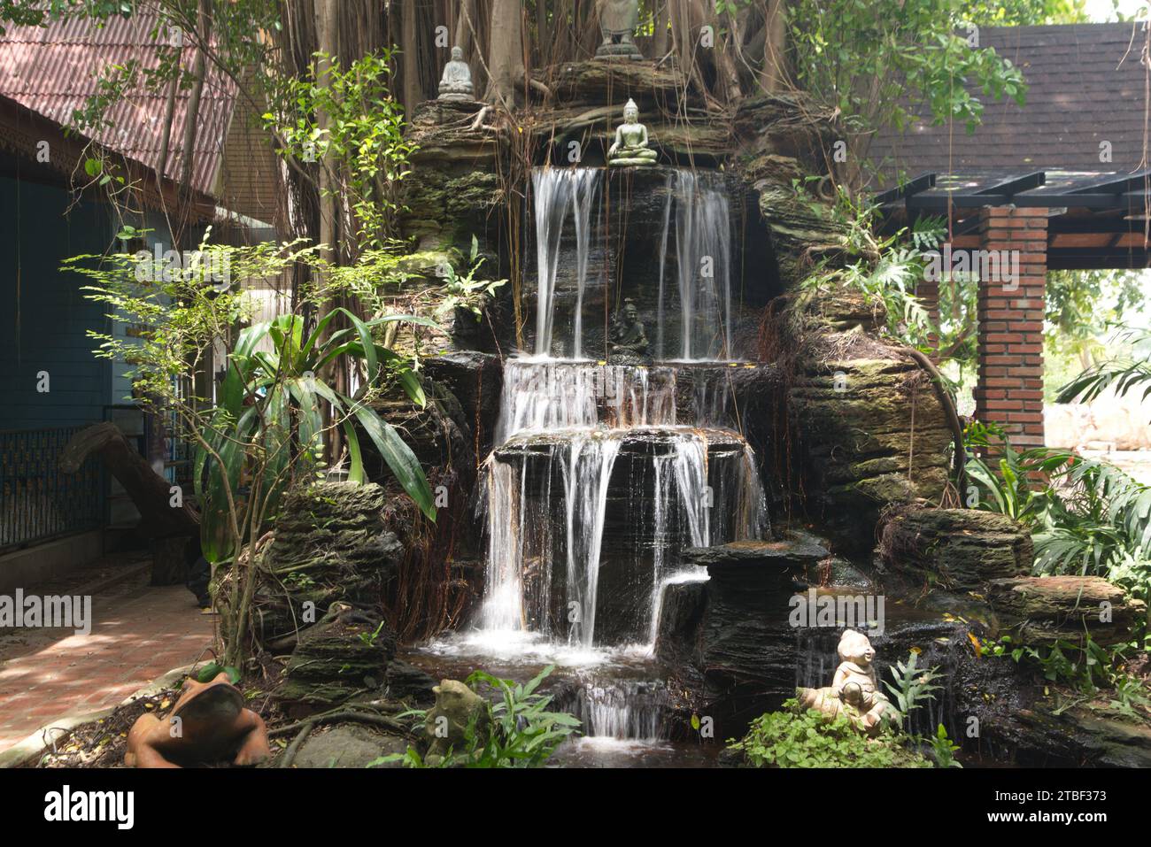 Waterfall is decorated with a small Buddha statue. At Wat Tha Mai temple. Located at samut Sakhon Province in Thailand. Stock Photo