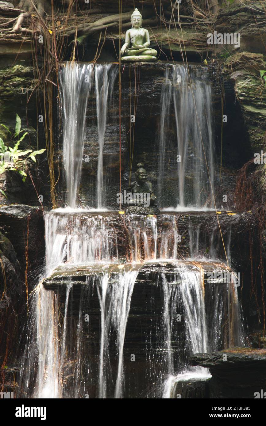 Waterfall is decorated with a small Buddha statue. At Wat Tha Mai temple. Located at samut Sakhon Province in Thailand. Stock Photo