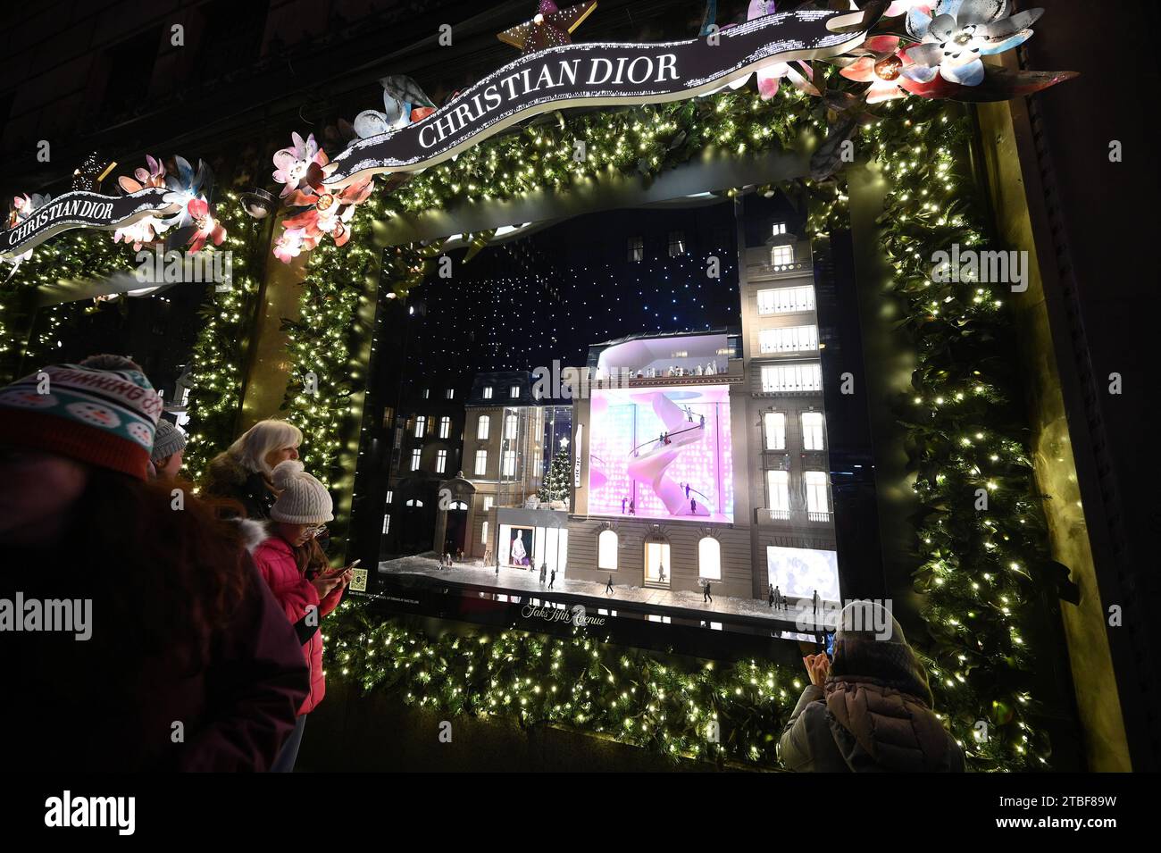 New York, USA. 06th Dec, 2023. People stop to look at the Saks Fifth Avenue department store Christmas holiday windows, New York, NY, December 6, 2023. Saks Fifth Avenue store is decorated in a cooperative theme with Christian Dior for the holiday season. (Photo by Anthony Behar/Sipa USA) Credit: Sipa USA/Alamy Live News Stock Photo