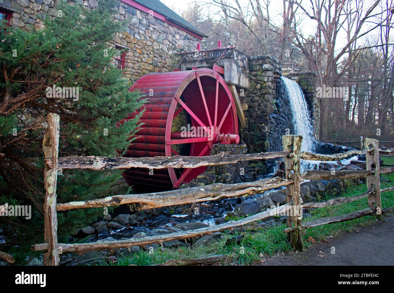 Historic landmark grist mill sporting a red wooden wheel, in Sudbury, Massachusetts, that is still in operation, producing cornmeal and wheat flourl - Stock Photo