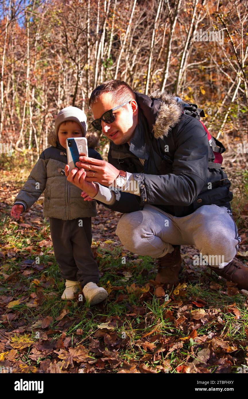 Father and his toddler using mobile phone in the forest Stock Photo