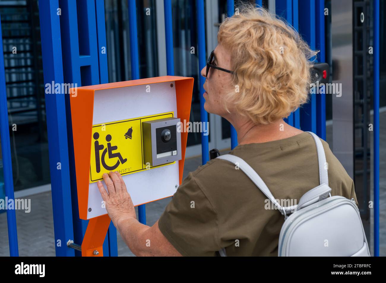 An elderly blind woman reading a text in braille. Button for calling