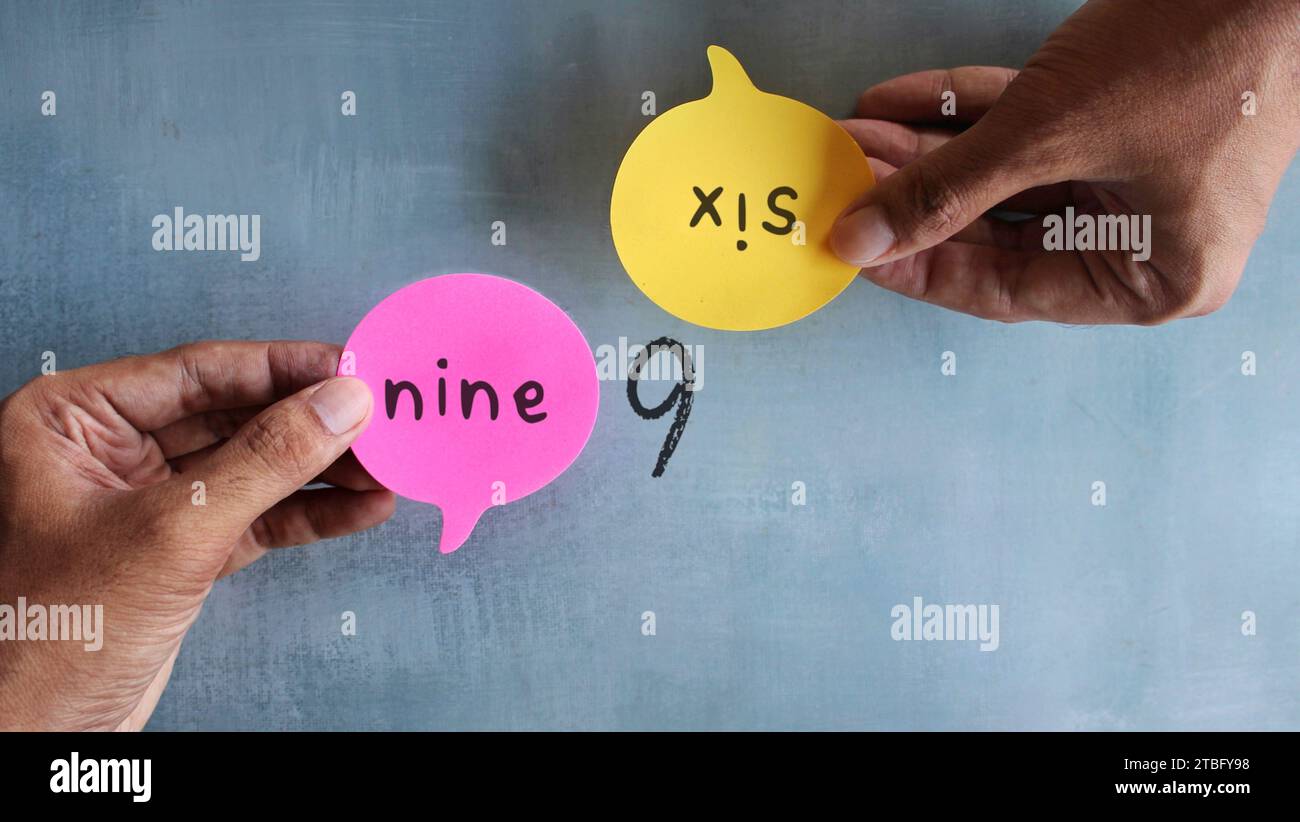 Hand holding speech bubble with text NINE and SIX. Different perception, perspective and argument Stock Photo