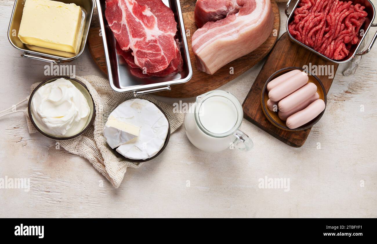 Saturated fats on tables. Raw meat, sausages, cheese, butter. Bad food