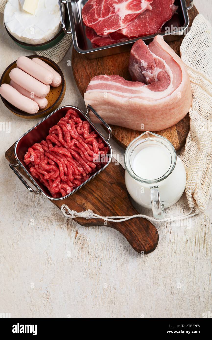 Saturated fats on tables. Raw meat, sausages, cheese, butter. Bad food