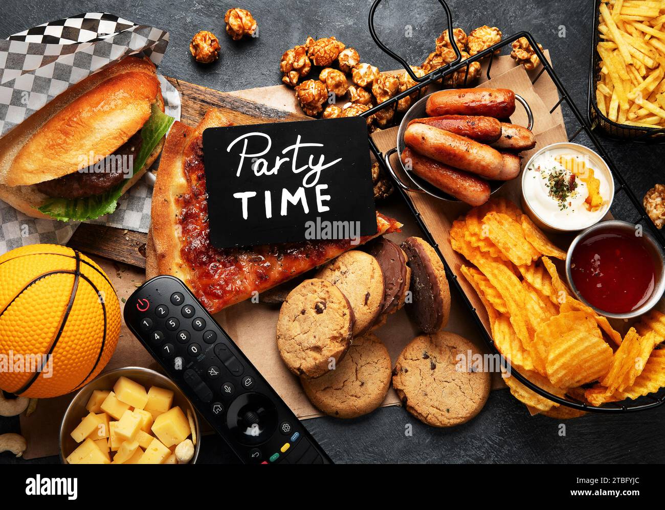 Unhealthy food i basket. TV remote control and snacks chips, popcorn