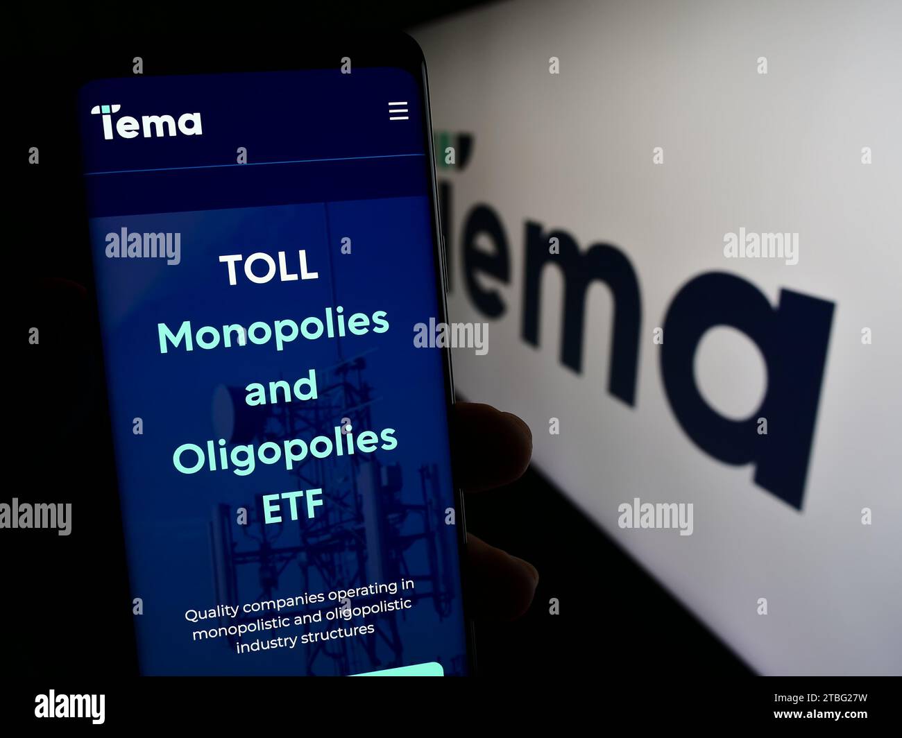 Person holding cellphone with webpage of US financial services company Tema Global Limited in front of logo. Focus on center of phone display. Stock Photo
