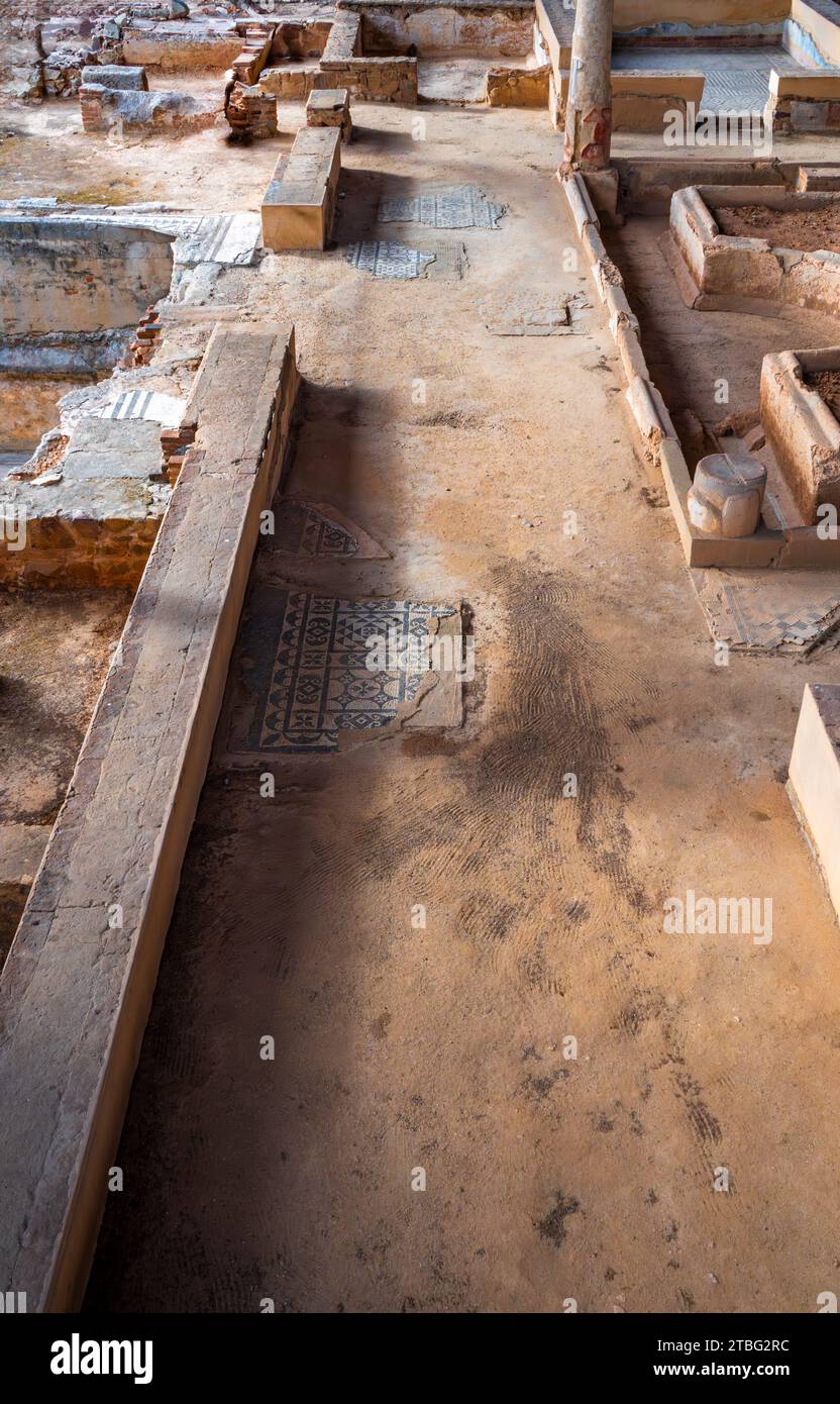 Archaeological remains of a hallway, rooms and Roman columns with remains of mosaics with blue geometric figures decorating the floors of the Mitreo h Stock Photo