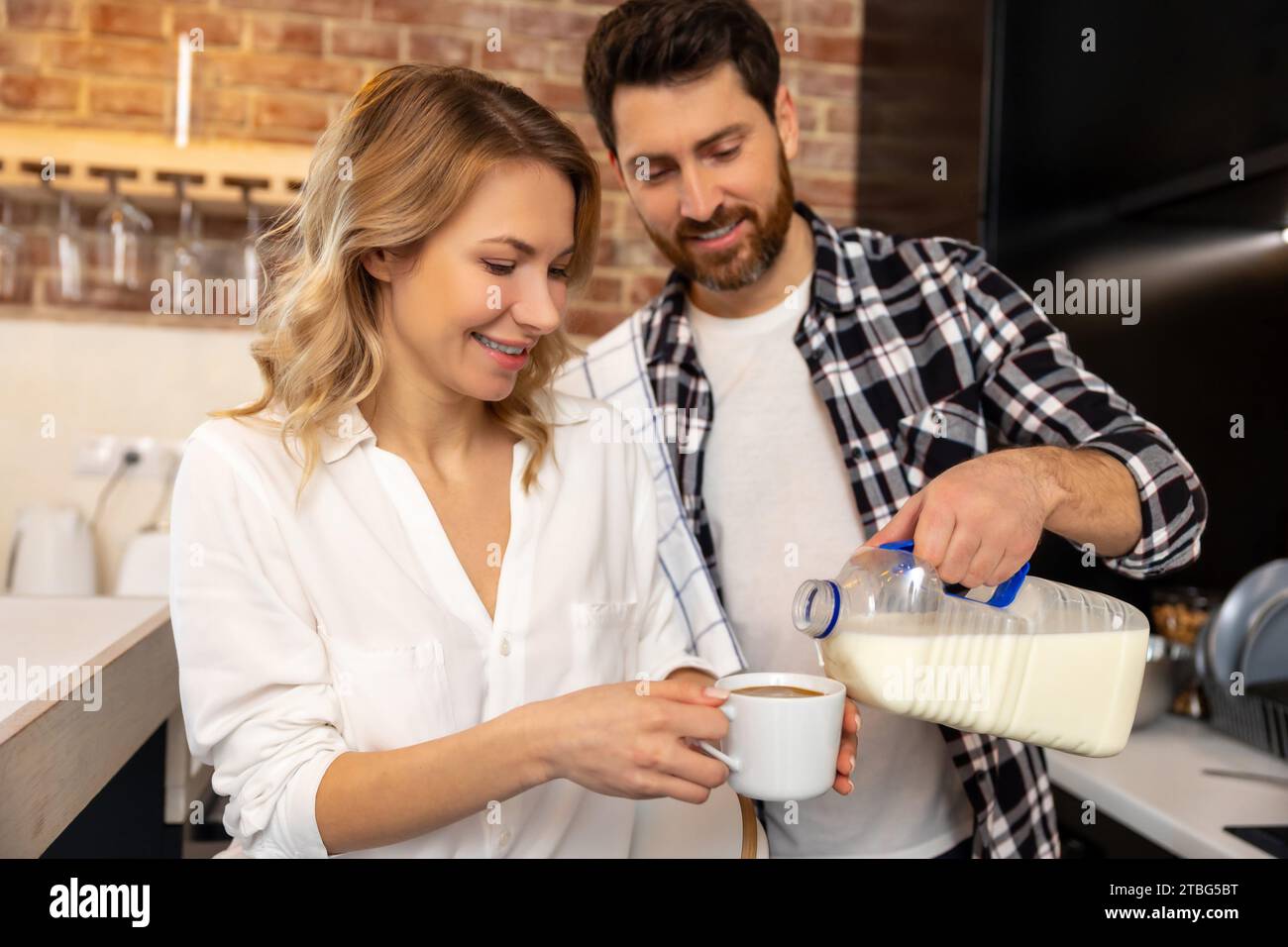 https://c8.alamy.com/comp/2TBG5BT/handsome-young-husband-adding-milk-or-coffee-creamer-to-his-girlfriend-cup-enjoying-breakfast-together-in-kitchenn-at-home-2TBG5BT.jpg