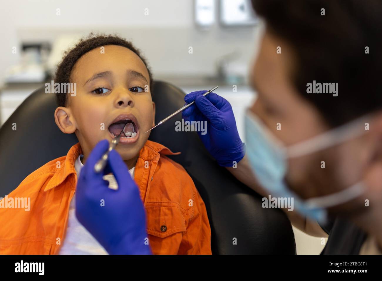 Caries treatment. Scared little boy sitting with open mouth at the