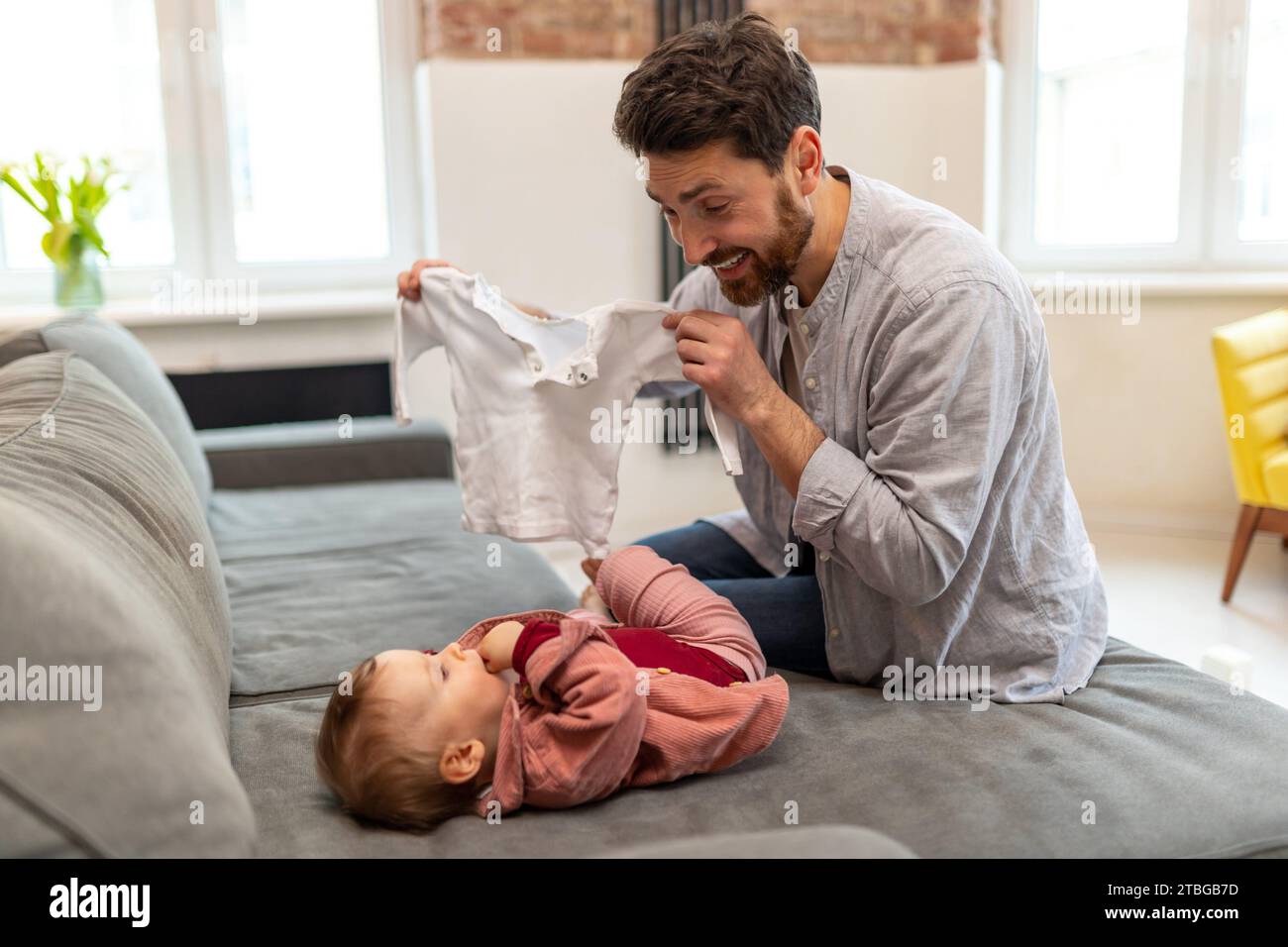 Father with toddler daughter at home, taking care of his baby changing