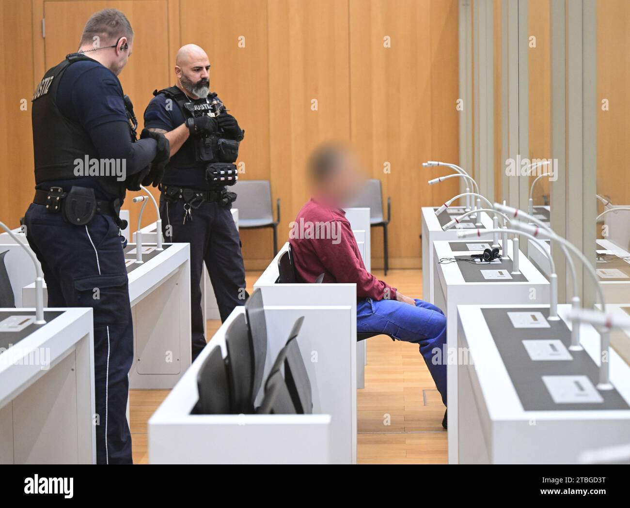 Stuttgart, Germany. 07th Dec, 2023. The defendant sits in a courtroom at the start of a trial for fifteen counts of attempted murder. Two rival groups have been waging a bloody feud in the Stuttgart area for many months, culminating in a hand grenade attack on a mourning congregation in Altbach near Esslingen. The Stuttgart public prosecutor's office has filed charges including attempted murder against the 23-year-old suspected grenade thrower. Credit: Bernd Weißbrod/dpa - ATTENTION: The defendant was pixelated by order of the court for reasons of personal privacy/dpa/Alamy Live News Stock Photo
