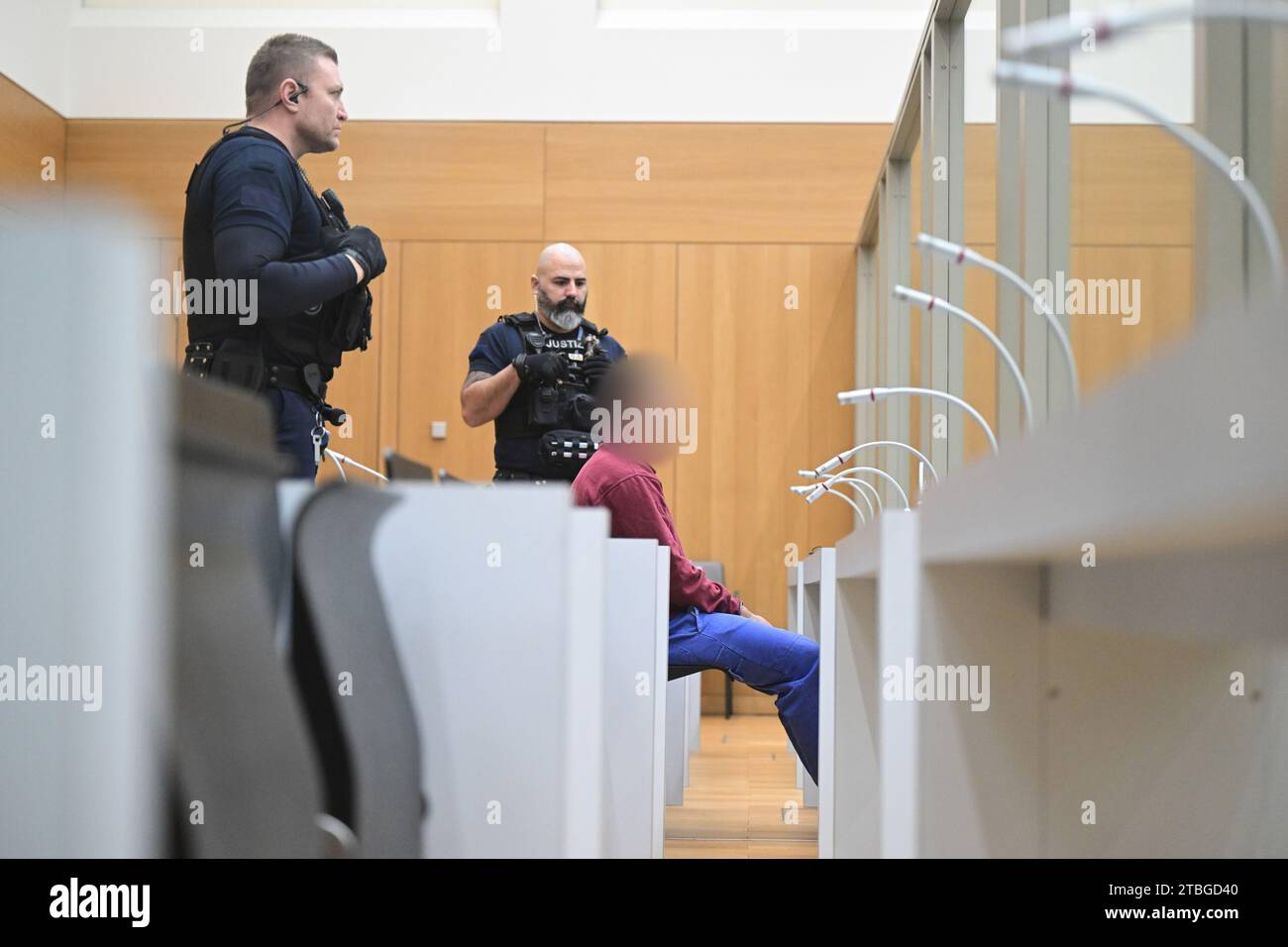 Stuttgart, Germany. 07th Dec, 2023. The defendant sits in a courtroom at the start of a trial for fifteen counts of attempted murder. Two rival groups have been waging a bloody feud in the Stuttgart area for many months, culminating in a hand grenade attack on a mourning congregation in Altbach near Esslingen. The Stuttgart public prosecutor's office has filed charges including attempted murder against the 23-year-old suspected grenade thrower. Credit: Bernd Weißbrod/dpa - ATTENTION: Defendant was pixelated by order of the court for reasons of personal privacy/dpa/Alamy Live News Stock Photo