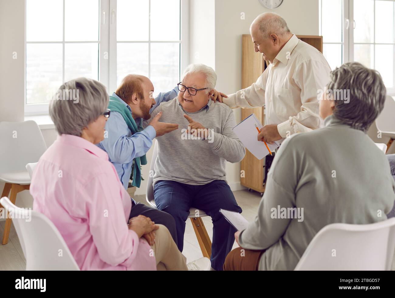 Two angry elderly people are talking and arguing at group therapy session meeting Stock Photo