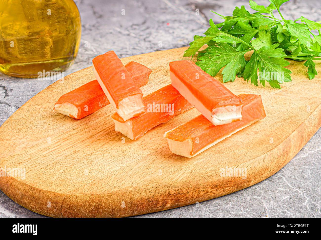 A cutting board with fresh surimi and whole green parsley Stock Photo