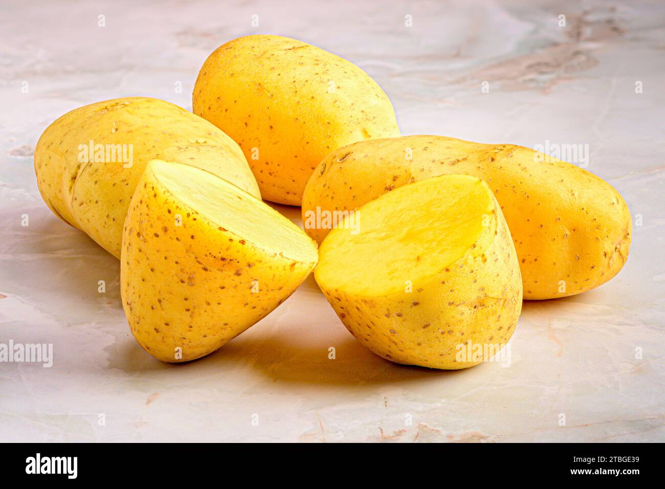 A closeup shot of potatoes, whole and sliced, on a countertop Stock Photo