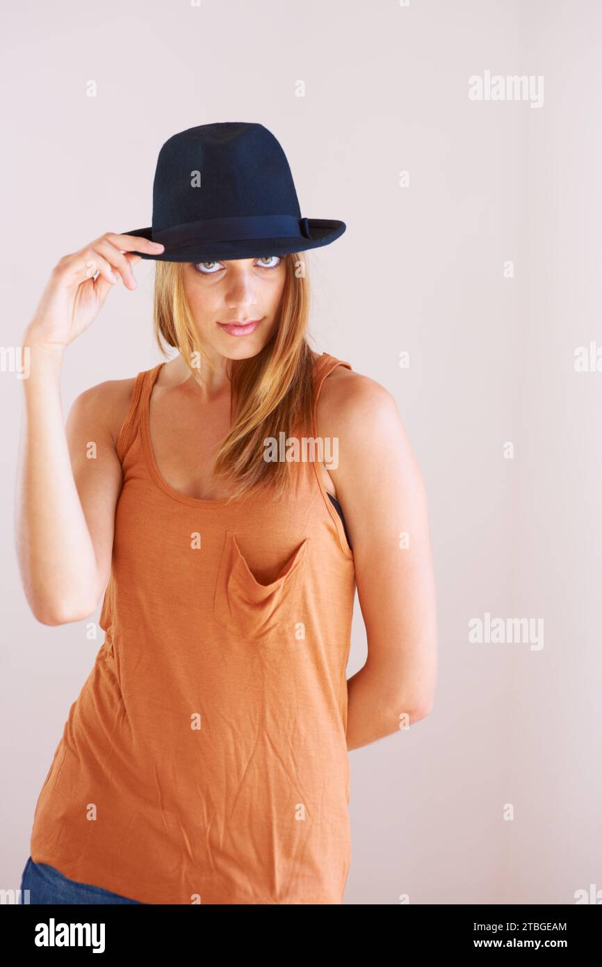 Fashion, portrait and woman with hat in studio for fancy or confidence with cool outfit on wall background. Face, attitude or female model pose with Stock Photo