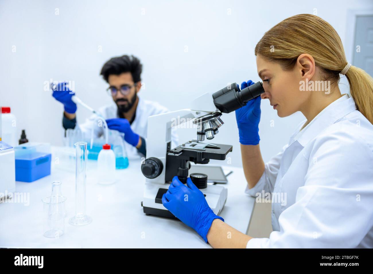 Researchers man and woman working with lab microscope for research