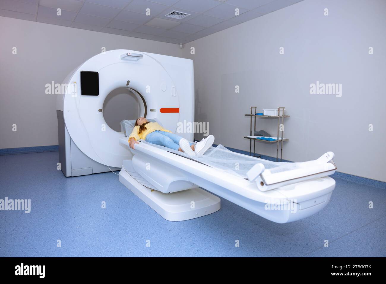 Little girl wearing casual clothing moving into mri scan machine before