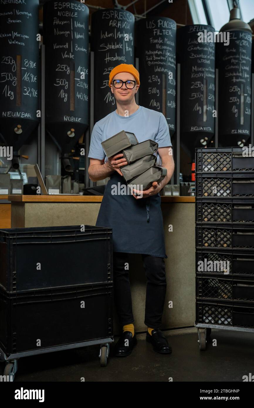 Barista bartender wearing hat and glasses unloads new batch of coffee