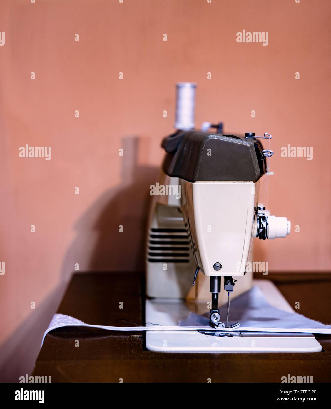 An old sewing machine situated on a wooden table in a home interior Stock Photo
