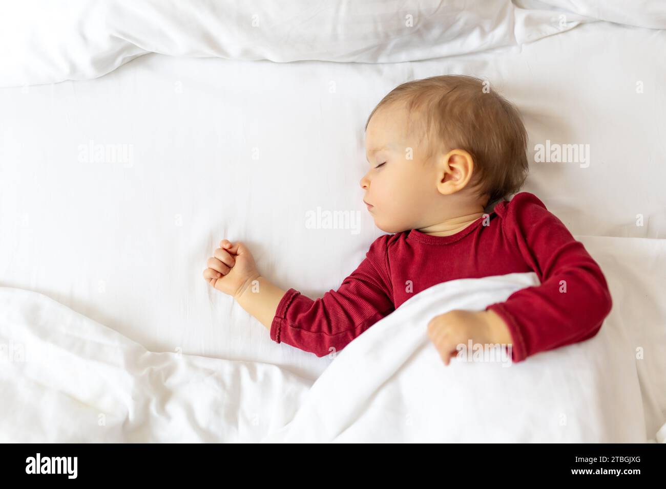 Infant baby sleeping in bed with white linen, children's daytime sleep