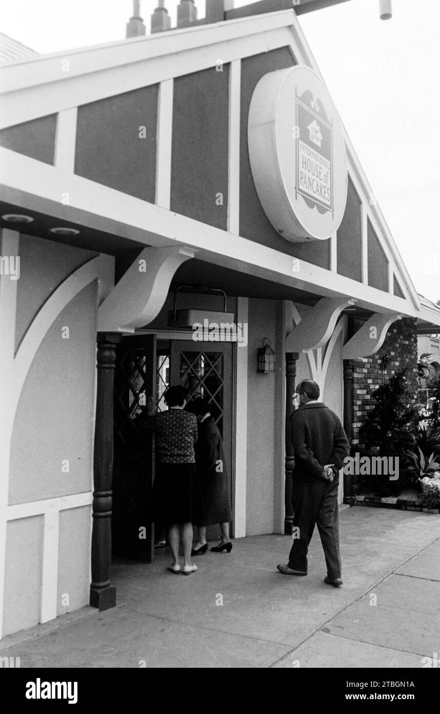 Drei Menschen betreten das International House of Pancakes, ein Pfannkuchenrestaurant in Los Angeles, 1962. Three people enter the International House of Pancakes, a pancake restaurant in Los Angeles, 1962. Stock Photo