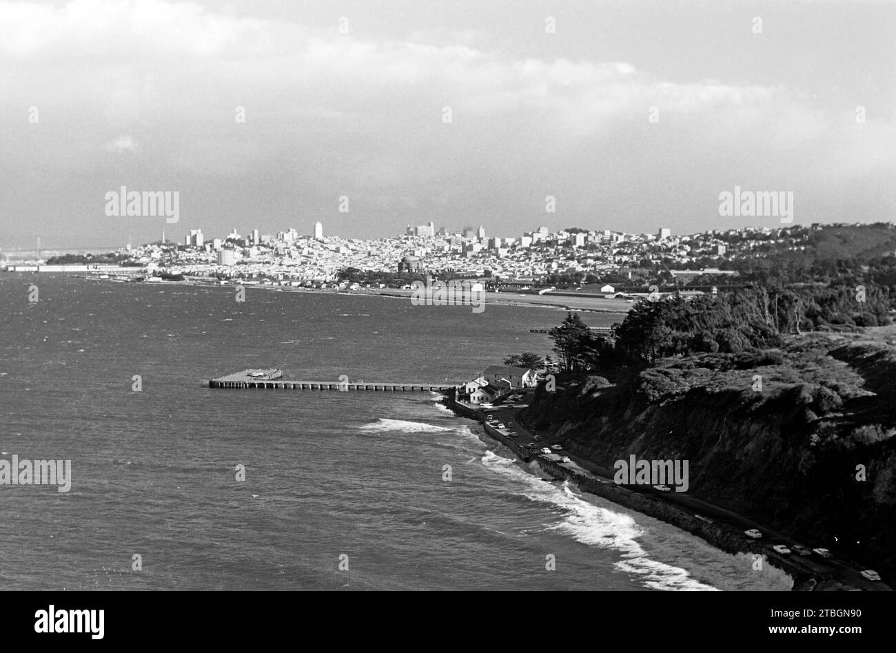 Blick von der Golden Gate Bridge auf die Skyline von San Francisco, rechts die Küstenstraße Long Avenue sowie mittig der Steg Torpedo Wharf, der ein beliebtes Ziel für Touristen und Angler darstellt, 1962. View of the San Francisco skyline from the Golden Gate Bridge, with Long Avenue on the right and Torpedo Wharf, a popular destination for tourists and anglers, in the centre, 1962. Stock Photo
