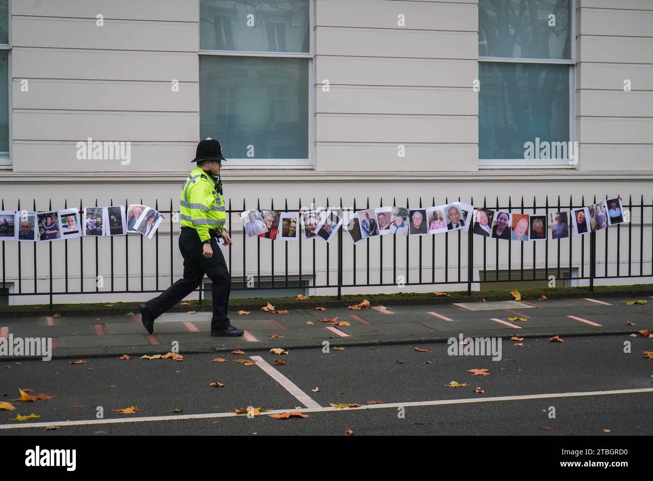 London UK. 7 December  2023. A Metropolitan Police Officer walks past the pictures of covid victims placed  by bereaved families  outside the Covid 19 hearing centre in central London as former Prime Minister Boris Johnson gives evidence for the second day  . Credit: amer ghazzal/Alamy Live News . Stock Photo