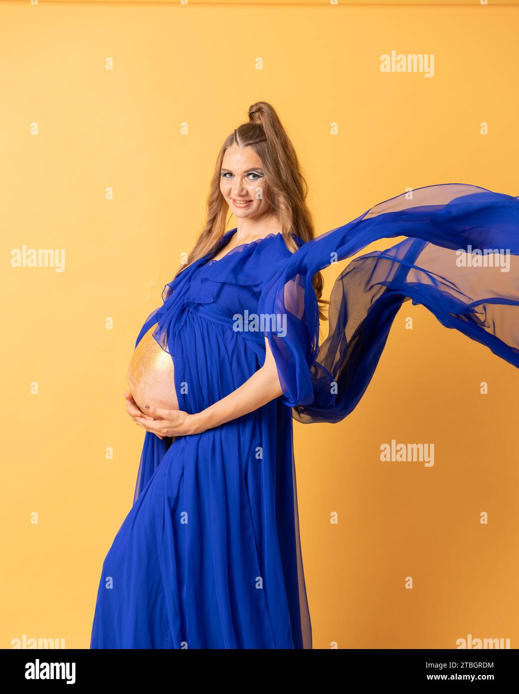 Pregnant woman on yellow background with big tummy, waiting for baby. Pregnancy, motherhood concept Stock Photo