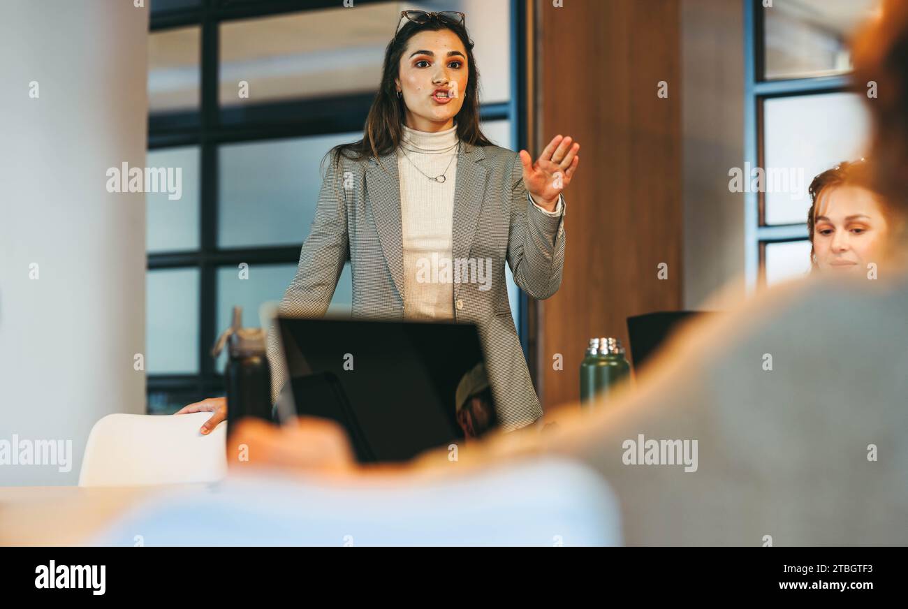 Diverse group of professionals brainstorm in a modern office. They discuss project management and exchange ideas, enhancing teamwork. Led by a busines Stock Photo