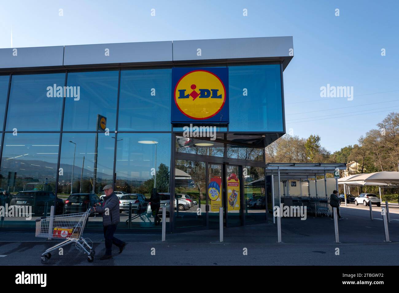 Old man with shopping cart passing by the facade of the Lidl supermarket in Seia, Portugal, Europe Stock Photo