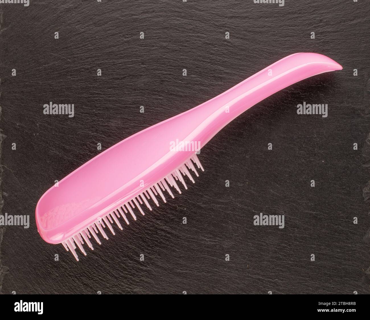 One pink plastic hairbrush on slate stone, macro, top view Stock Photo