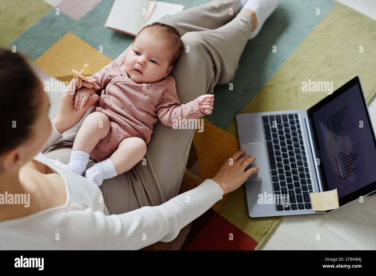 Curious Adorable Newborn Looking at Working Mom Stock Photo