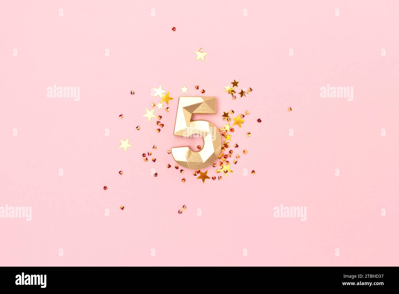 Golden number five and stars confetti on a pink background. Festive creative concept. Stock Photo