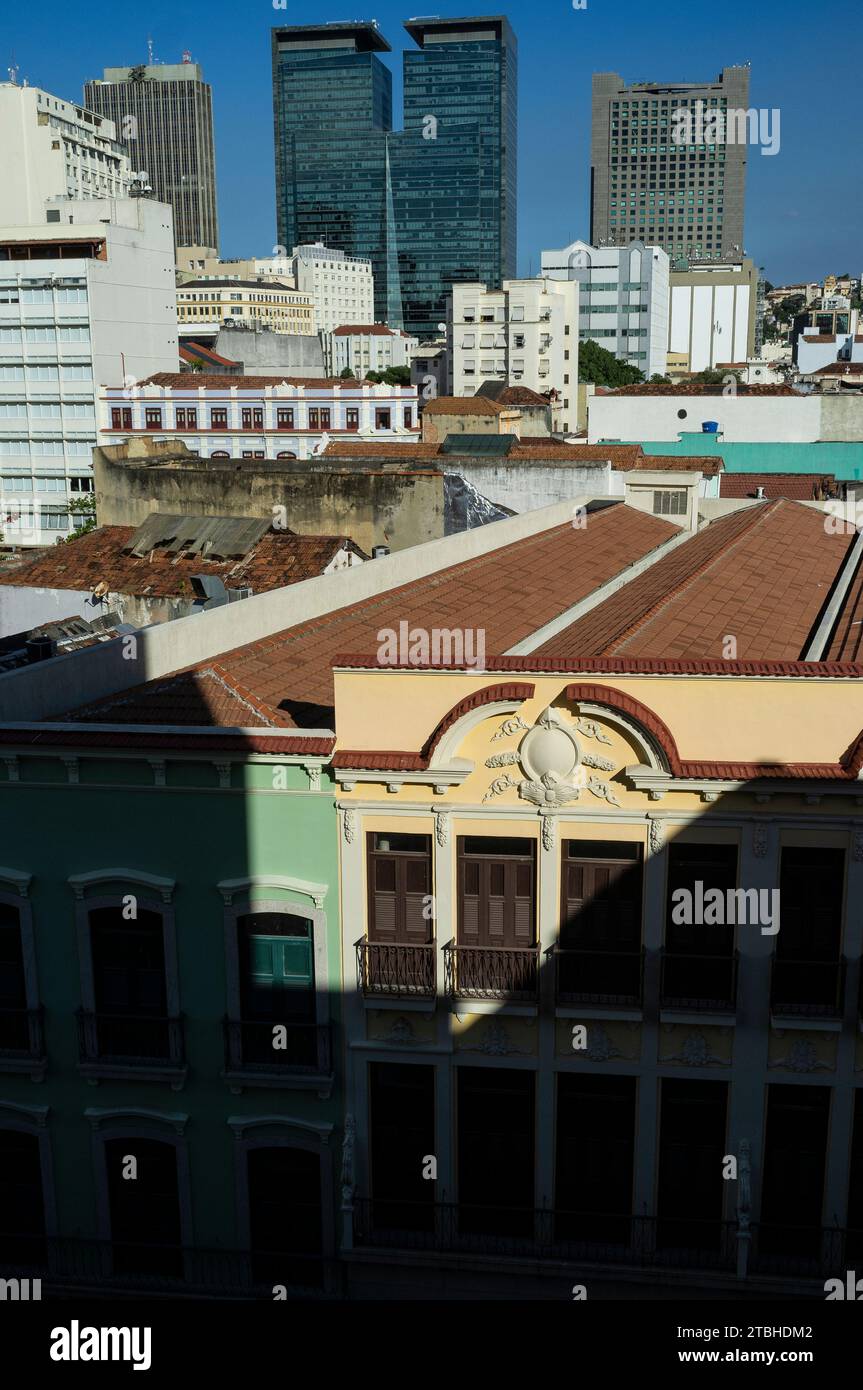 Urban contrast - preserved sobrados, two or more story ancient houses from the colonial and imperial periods in Brazil at Rua Buenos Aires ( Buenos Aires street ) at the heart of the popular commerce region known as Saara in downtown Rio de Janeiro, next to corporate modern buildings. Ventura Corporate Towers (left) and Rio Metropolitan Building in background. Stock Photo